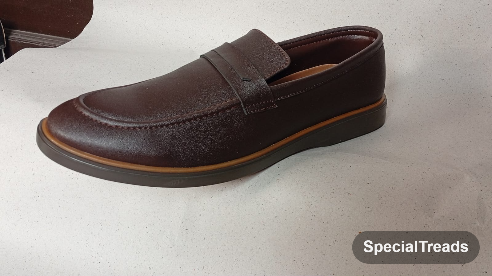 Dark brown penny loafer with tan welt and saddle strap