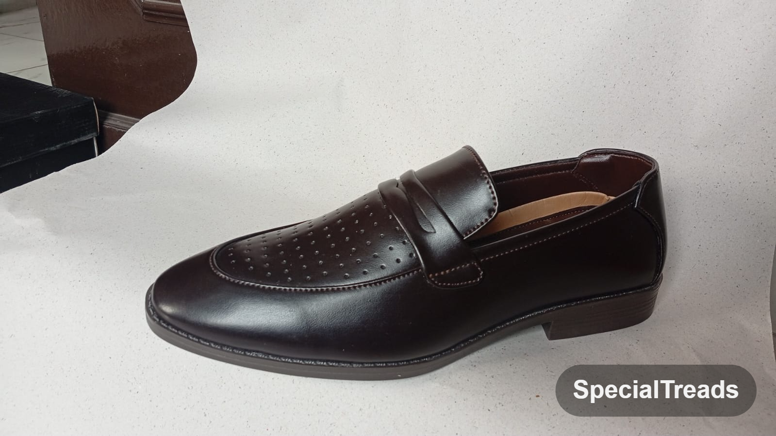 Dark brown perforated penny loafer with saddle strap and stacked heel