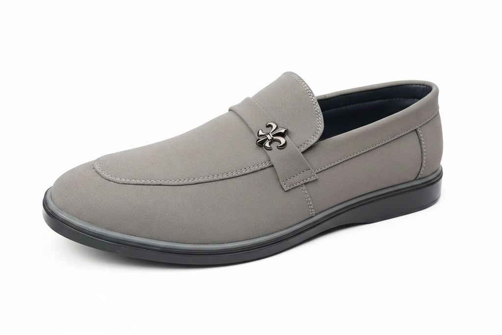 Light grey suede loafer close-up showing fleur-de-lis emblem and toe detail