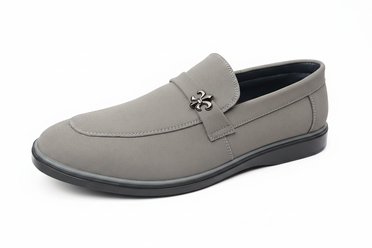 Light grey suede loafer close-up showing fleur-de-lis emblem and toe detail